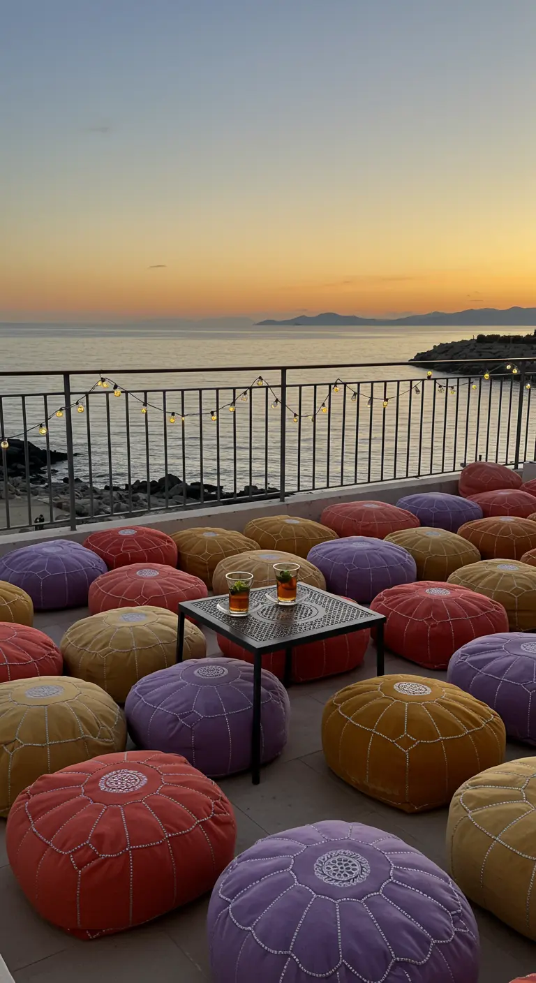 A variety of colorful poufs on a balcony with a sea view at sunset.