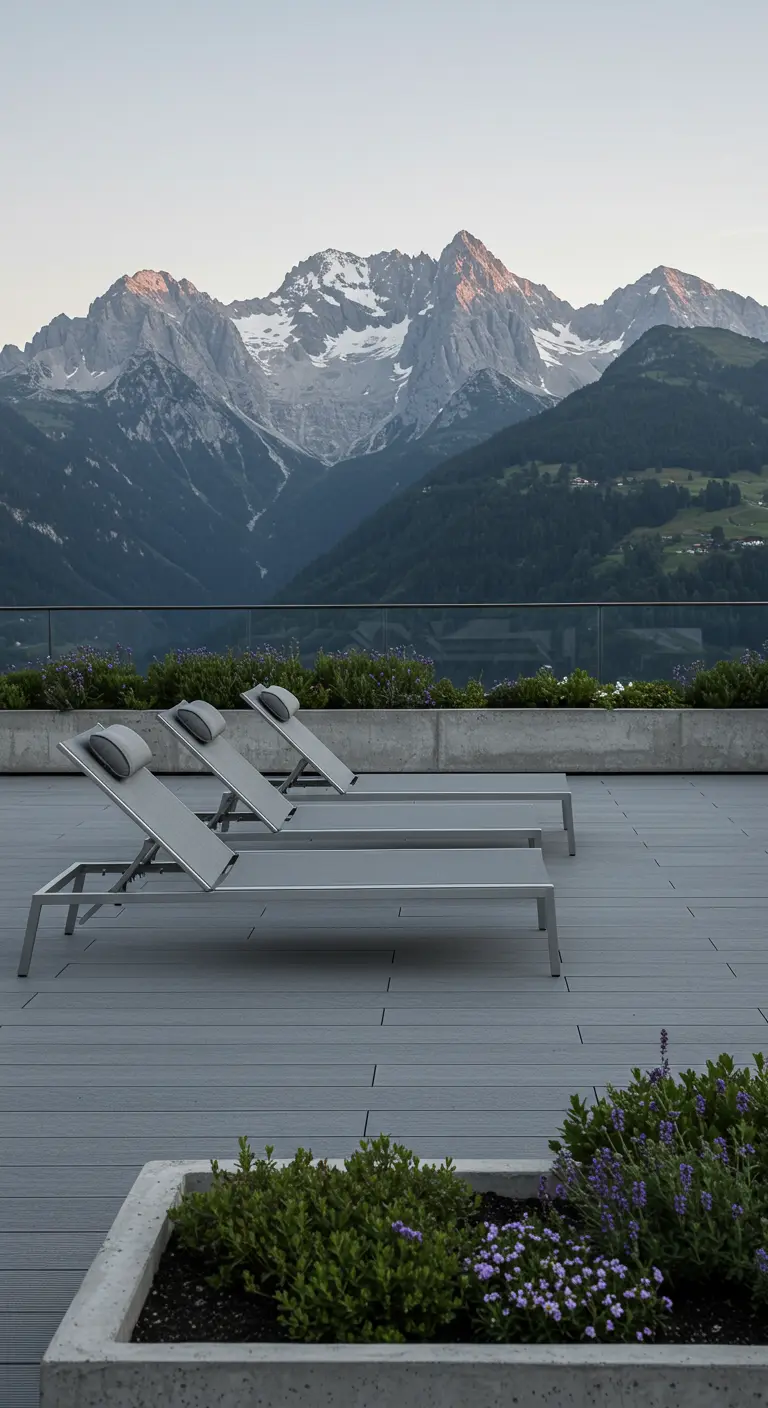 Three sleek silver aluminum chaise lounges on a deck facing a majestic mountain range.