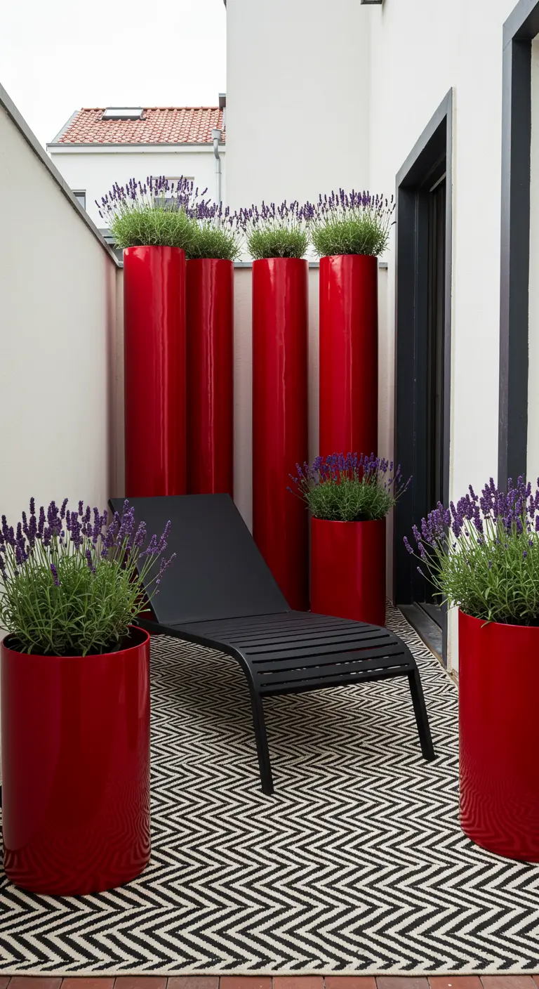 A sleek black chaise lounge on a graphic black-and-white rug, surrounded by tall, glossy red planters.