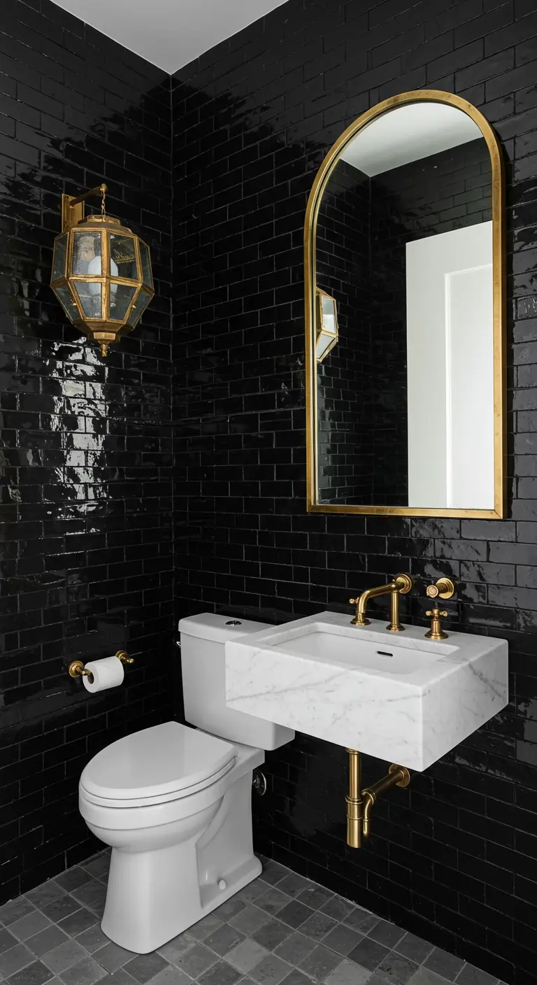 Small powder room with glossy black tiles, a marble sink, and brass fixtures.