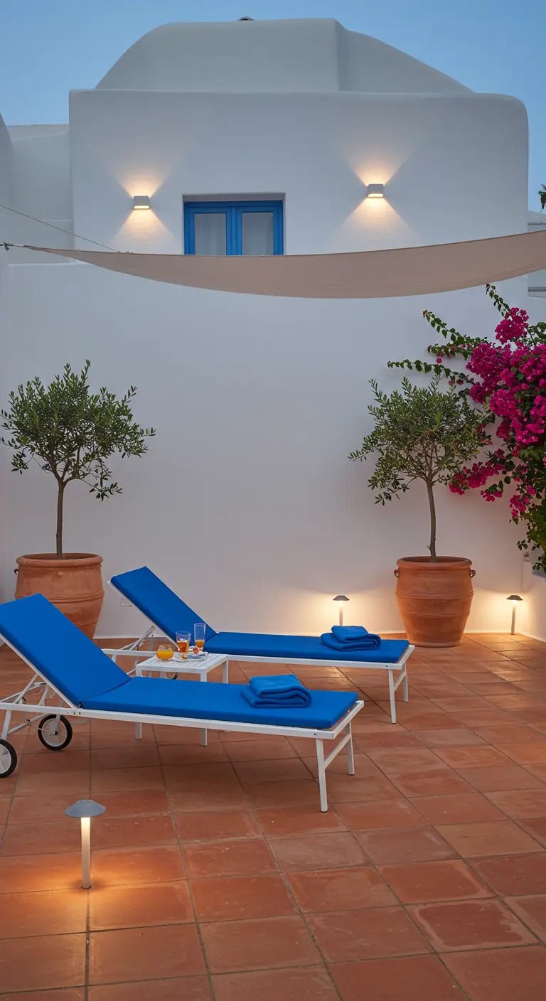 Blue sunbeds on a terracotta patio with olive trees and white walls in Mediterranean style.