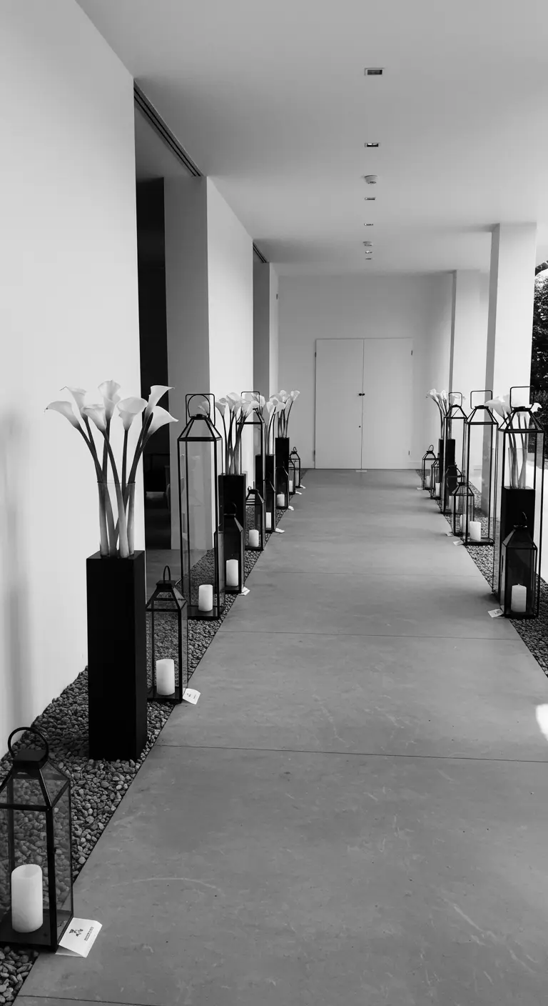 A minimalist black and white hallway with calla lilies and lanterns.