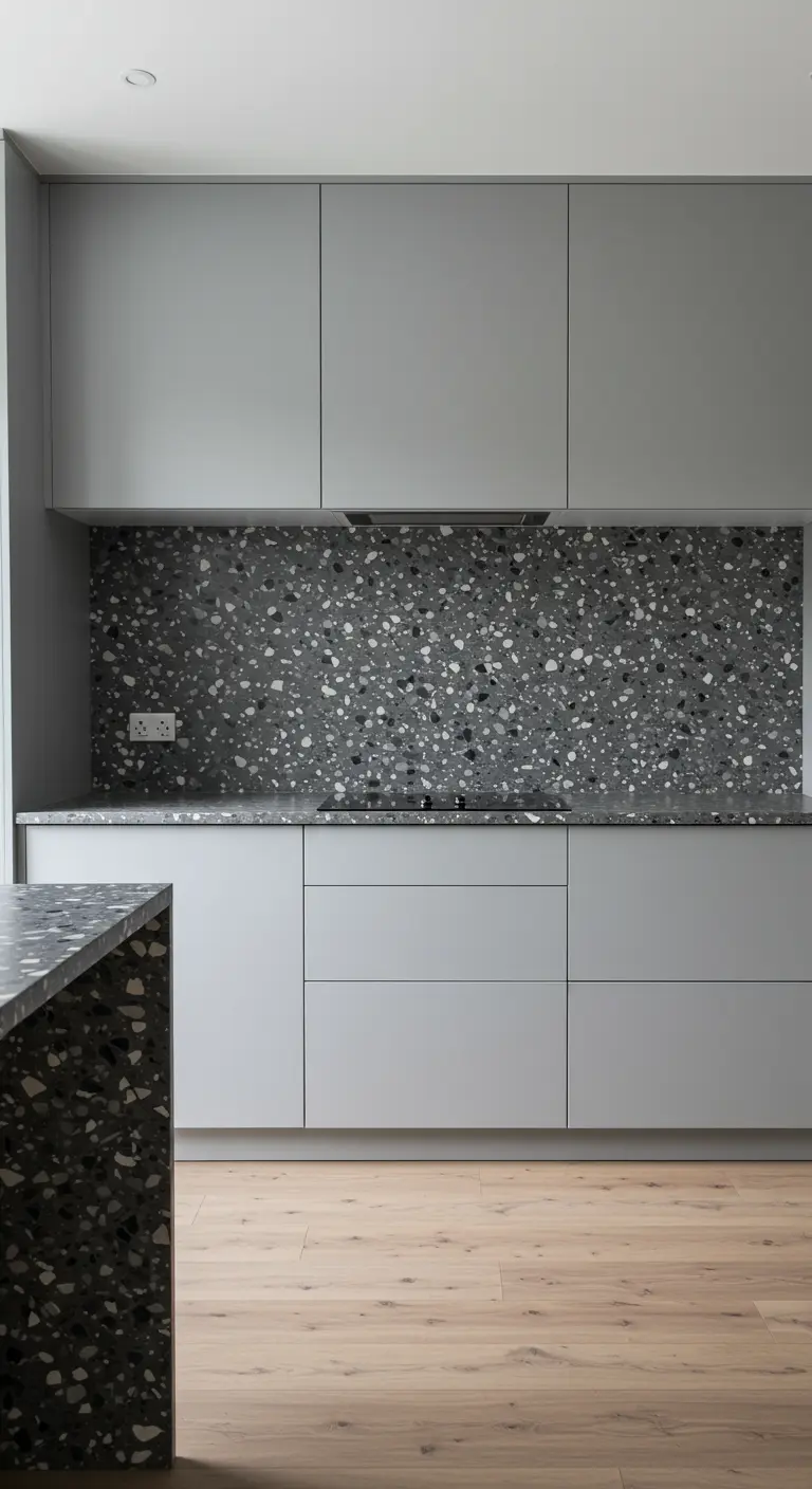Kitchen with light grey cabinets and a bold grey terrazzo backsplash and waterfall island.