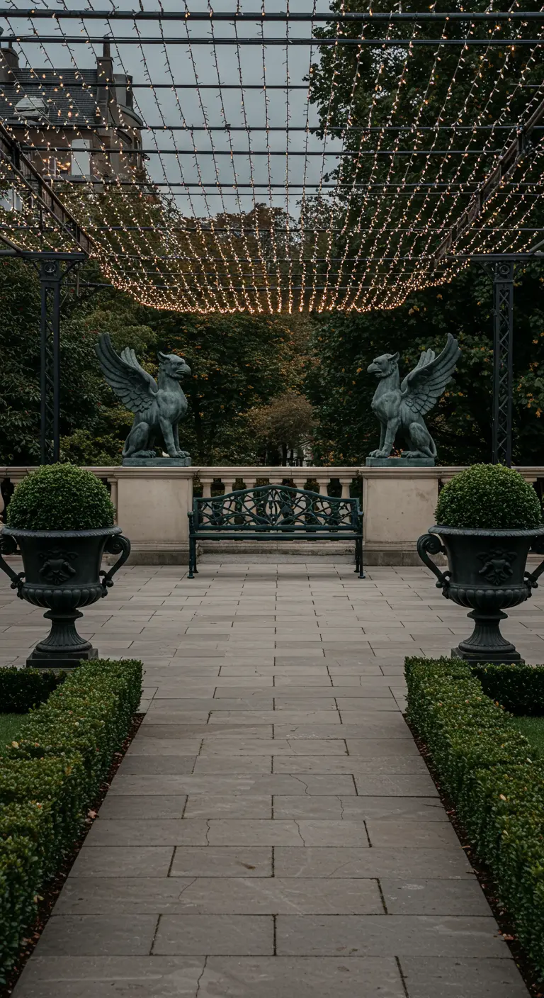 A formal stone path flanked by matching gryphon statues and urns under a canopy of lights.