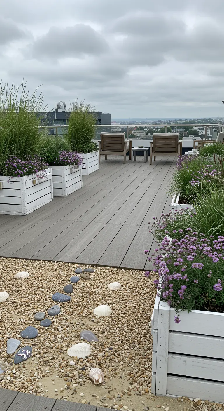 A rooftop deck with white planters, grasses, and a gravel section with seashells.