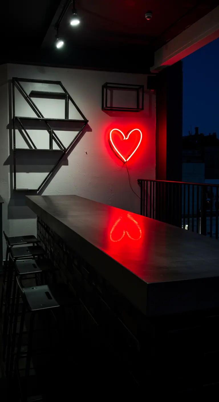 A dark balcony bar with a sleek countertop reflecting a bright red neon heart.