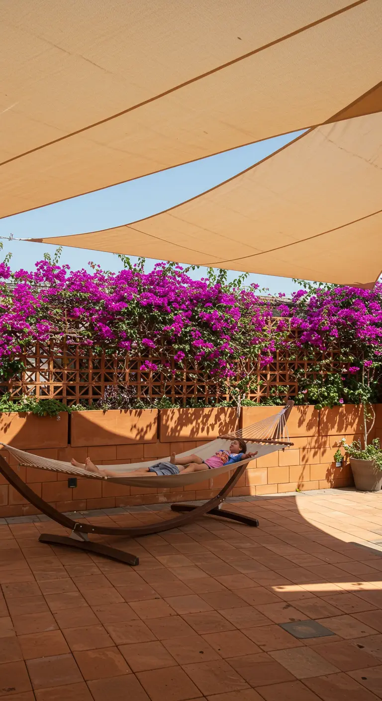 A person relaxing in a hammock on a tiled patio, shaded by a large beige sun sail.