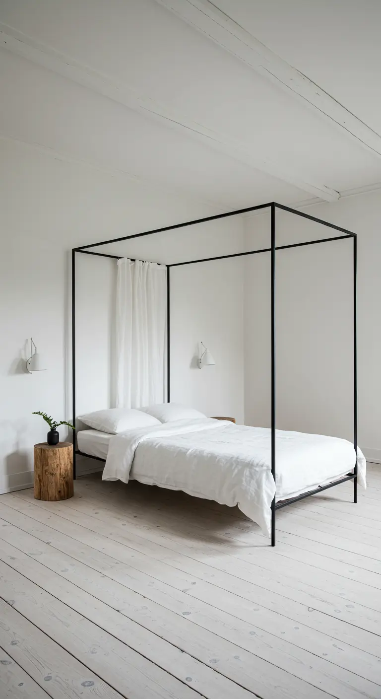 Minimalist white bedroom with a slim, black metal canopy bed and whitewashed wood floors.
