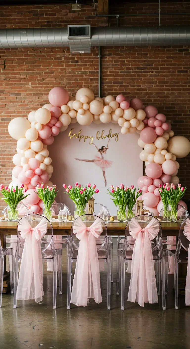 A party table set under a large balloon arch in shades of pink and cream.